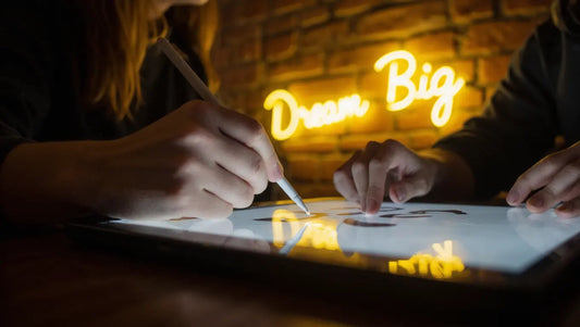 A designer uses a tablet to design your own neon sign, showing the digital mockup next to the finished, glowing product.